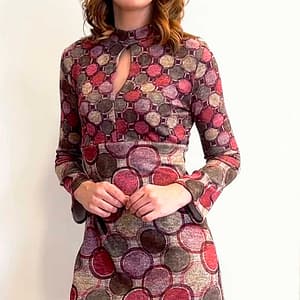 Fotografía de una mujer con un vestido de manga larga con círculos de diferentes colores.