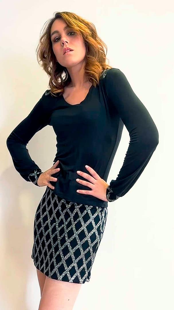 Mujer con un jersey negro y una falda con detalles de color plata.