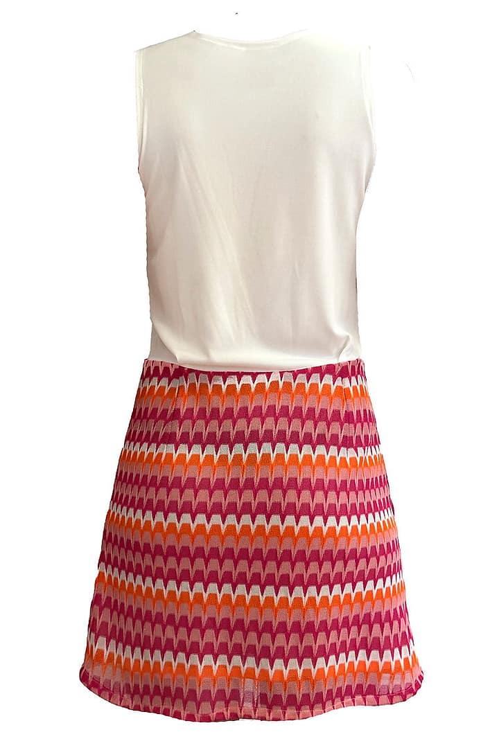 Fotografía de un vestido visto desde detrás con la parte de arriba blanca y la parte de abajo con una falda con detalles rosas, naranjas y blancos.