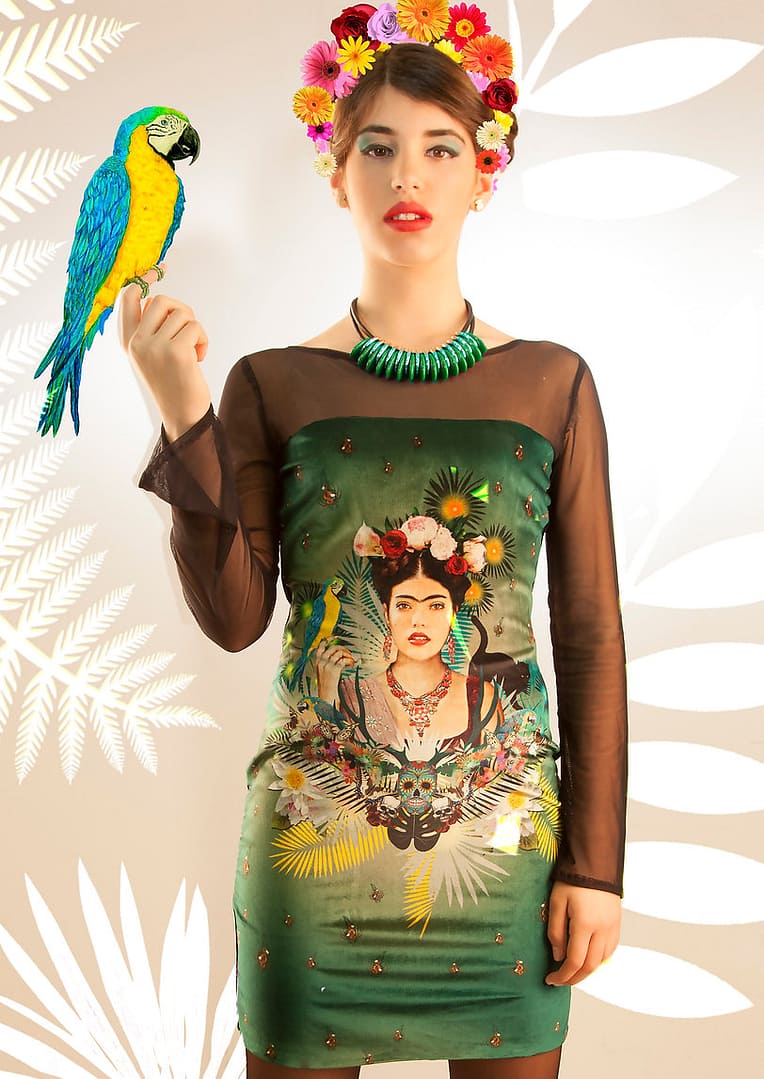 Fotografía de un vestido, donde se ve que una parte de la espalda y los brazos son con una tela transparente y el resto de vestido es con tela terciopelo, donde tiene impreso un montaje con diferentes motivos de Frida Kahlo y el rostro de ella en el centro.